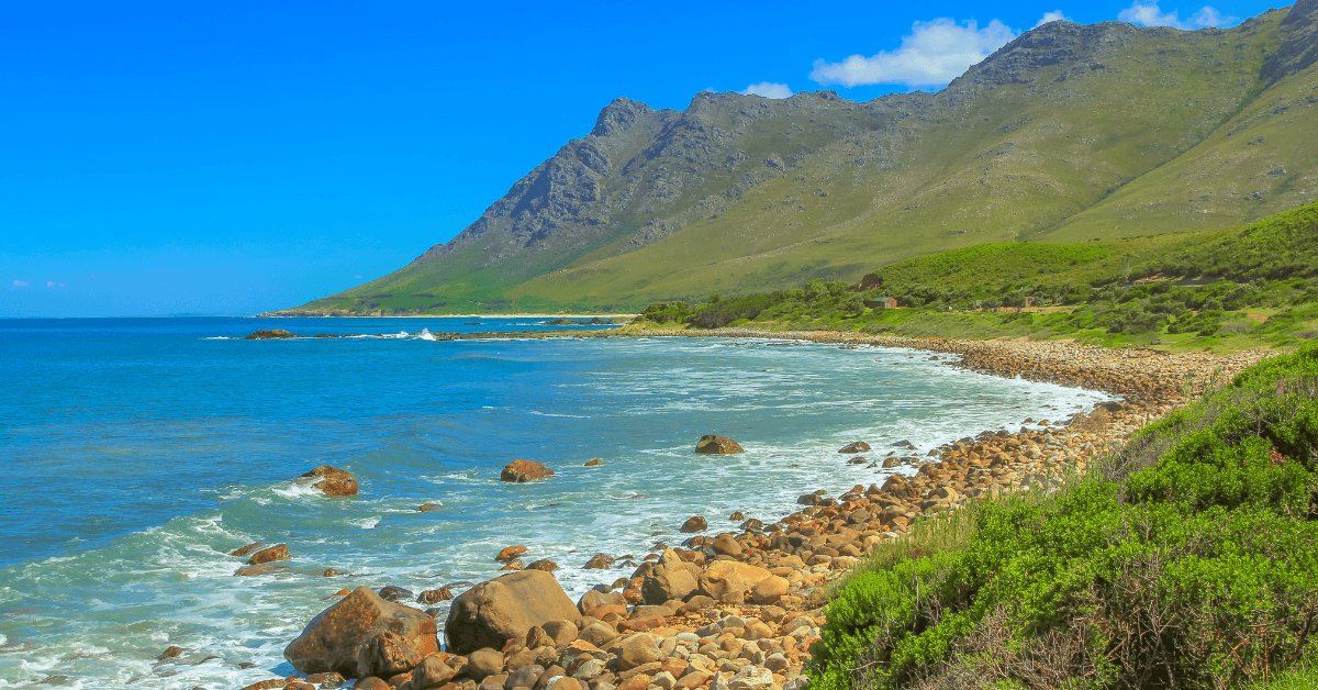 Scenic coastal view of Pringle Bay with rocky beach , clear water and green mountains 
